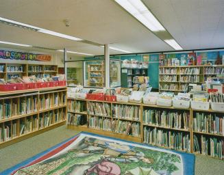 A photograph of a public school library, with bookshelves on the floor and against the walls.