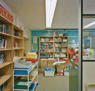 A photograph of an office, with bookshelves and storage bins.