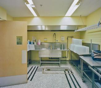 A photograph of a cafeteria kitchen, with a sink and metal tables.