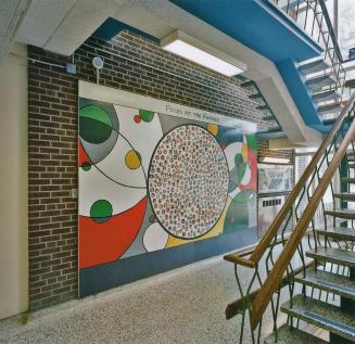 A photograph of a public school hallway, with a mural entitled "Faces Of The Future" …