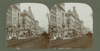 Pictures show a busy downtown street with tall office buildings to the left.