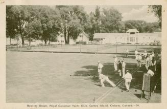Black and white shot of many men dressed in white lawn bowling on a fenced in green.