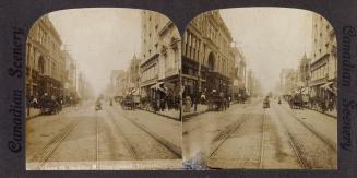 Pictures show street car tracks going up a city street with large buildings on both sides.