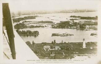 Black and white photograph shot from a plane of lagoons and land with a few buildings. Lighthou ...
