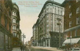 Colorized photograph of a corner of a eight story hotel building on a busy street.