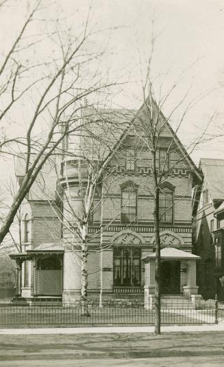 Black and white photograph of a large, three story Victorian house. Light colored brick.