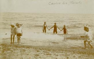 Sepia toned picture of 6 children paddling in a lake.