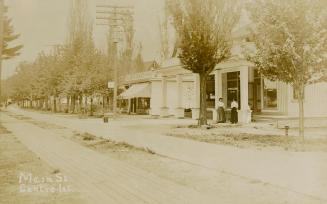 Sepia toned picture of stores on a country street with a wooden plank boardwalk.