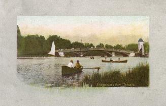 Colorized photograph of people in row boats on a lagoon; bridge in background