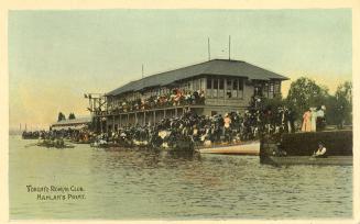 Colorized photograph of a large group of people watching a boat race from the shore and the bal ...