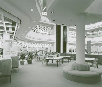 Picture of tables and large study area in the Metropolitan Toronto Library with two people seat ...