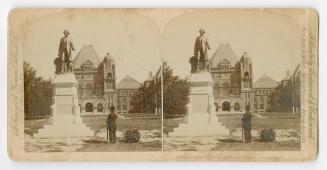 Pictures show a man looking at a bronze stature of a man on a pedestal in front of a very large ...