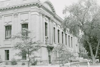 Picture of the side view of a large two story library building with large tree in front.