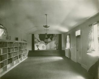 Photo of library theatre room with bookshelves on left wall and a small stage and painted mural ...