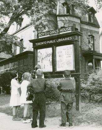 Group of boys and girls looking at display sign for the Boys and Girls House 