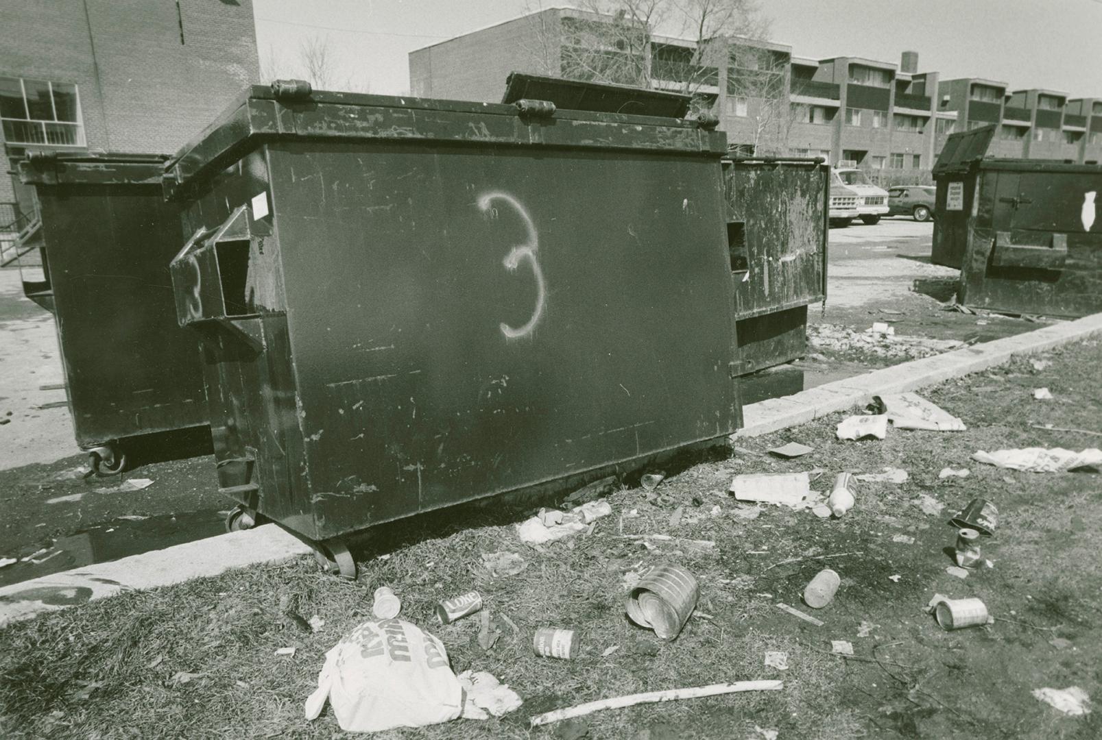 Photograph of garbage disposal bins in Flemingdon Park, with townhouses in background (black an…