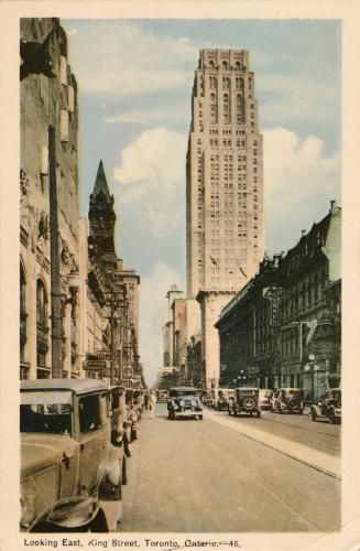 Colorized photograph of a street in a busy downtown with many cars on the road.

