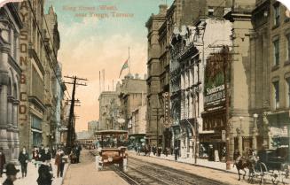 Colorized photograph of a busy downtown street with a motorcar in the foreground.
