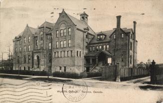 Black and white photograph of a four story school building adjacent to a large house.
