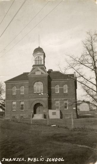 Black and white photograph of a two story school with a central bell tower.
