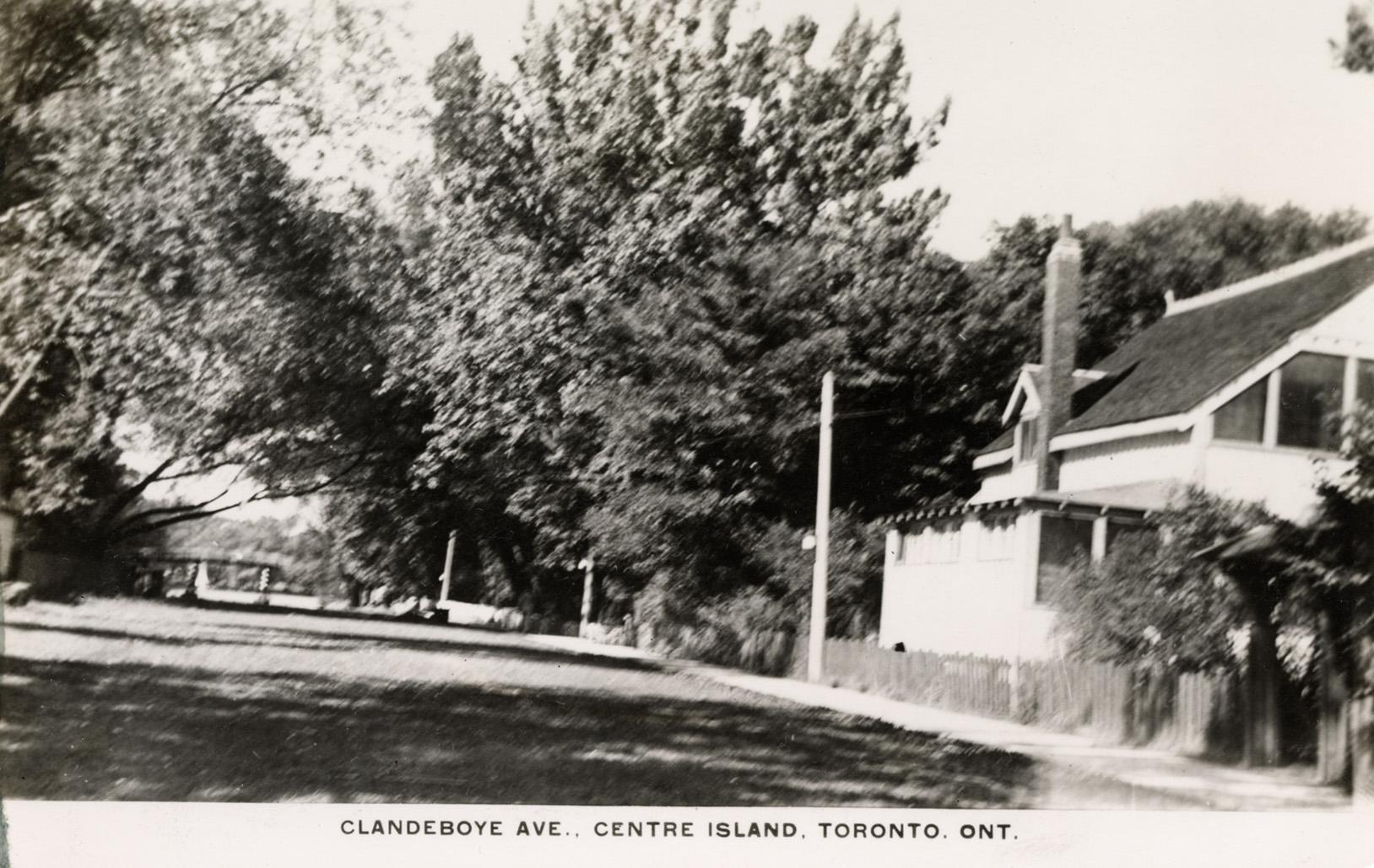 Black and white photograph of the side of a cottage with a walkway beside it.
