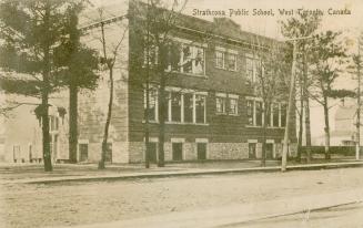 Sepia tone photograph of a three story, square school building.