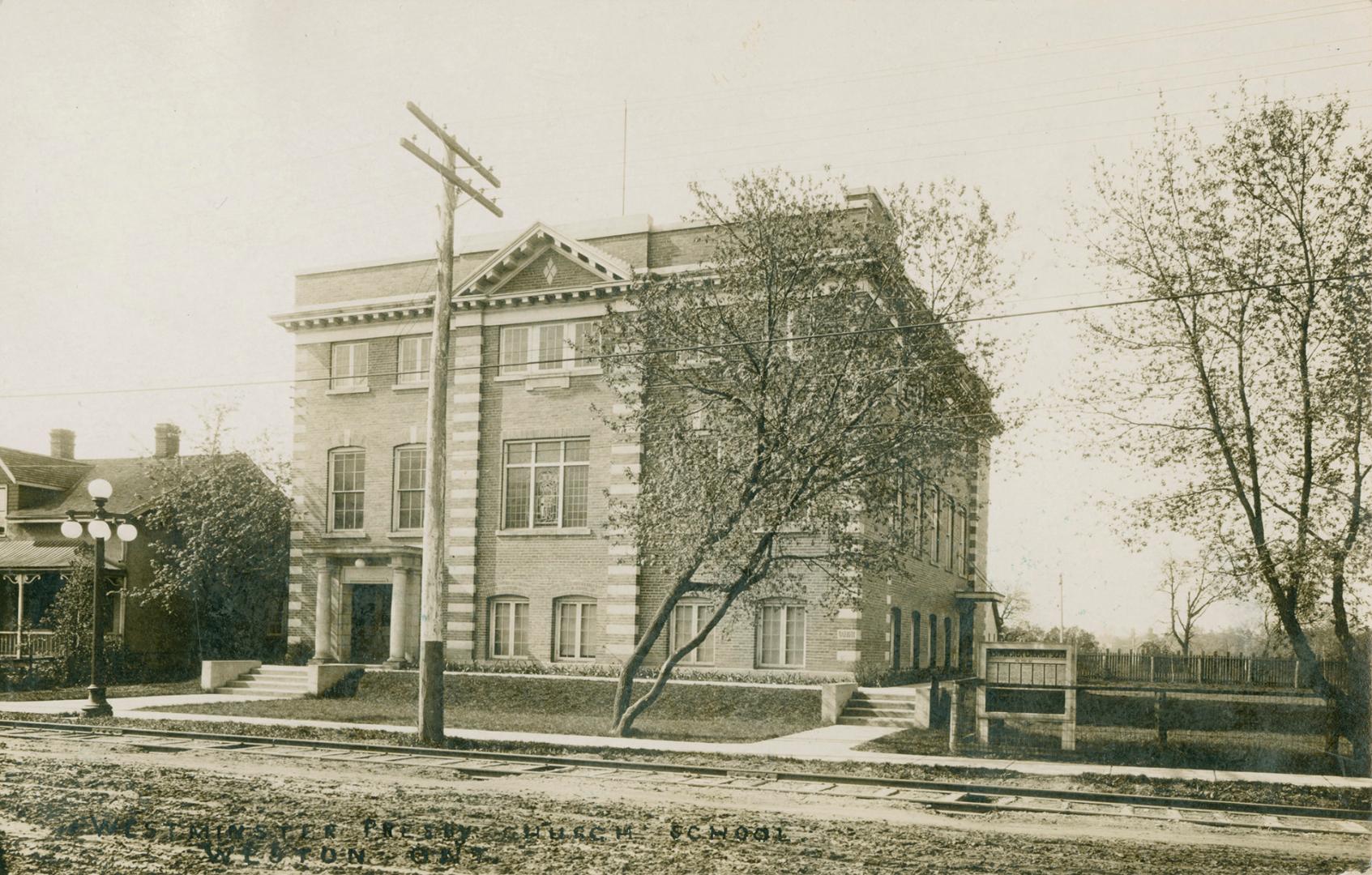 Black and white picture of the three story, square building with steps and a walkway in front o…