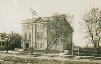 Black and white picture of the three story, square building with steps and a walkway in front o…