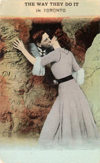Colorized picture of a man and woman kissing through an opening in a rock wall.
