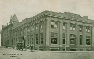 Black and white photograph of the two story commercial building taken from a downtown corner. 
