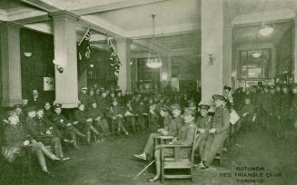 Black and white phot graph of a large group of uniformed men gathered together in an open room.