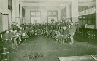 Black and white photograph of a group of men in uniform gathered together in an open room.