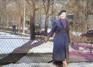 Photo of Lillian Smith standing against a fence in winter with houses behind her. 
