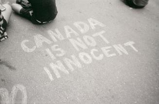 A photograph of a message reading &quot;CANADA IS NOT INNOCENT&quot; written on pavement in cha ...