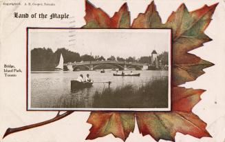 Boaters with bridge in background. Postcard background is a large maple leafe with caption "Lan ...