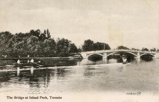 View across a Toronto Islands waterway looking toward bridge. Includes boaters: rowboat with tw ...