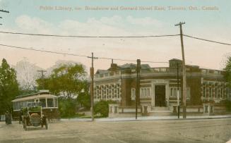 Picture of street with library on the corner, streetcar and car. 