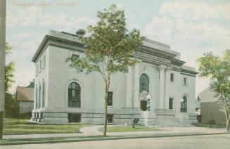 Picture of large two storey public library building with tree in front. 