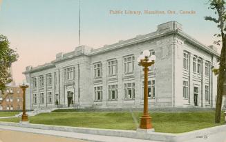 Picture of large grey stone two story library with street lamps out front. 