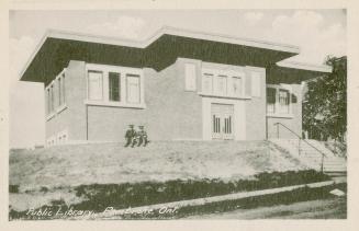 Picture of a one storey library building set on a slight hill and two soldiers sitting out fron…