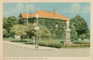 Picture of an ivy covered two storey library building on a street croner with cenotaph statue,  ...