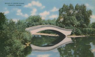 Bridge over water surrounded by large trees. 
