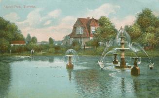 Picture of a lagoon with large fountain and a cottage in the background. 