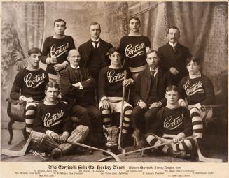 A formal photograph of a hockey team, taken in a studio, with the players and administrative st…