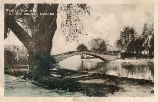 Black and white photograph of a curved bridge over a narrow body of water.