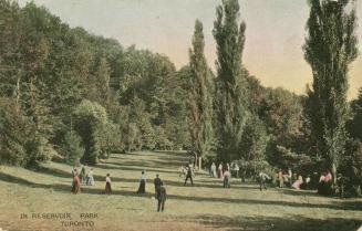 Park scene of a small gathering of adults in Reservoir Park. The people are standing on on a wi ...