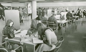 Picture of people sitting at study tables in a library. 