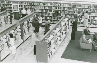 Picture of people browsing shelves of books in a library.