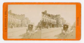 Pictures show commercial buildings on the south side a street with a horse and buggy in the for ...