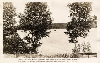 Black and white picture of a shoreline of a lake with a sailboat on it.